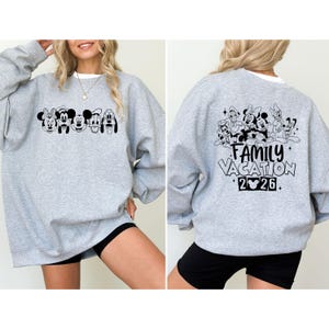 May include: A light gray sweatshirt featuring a black graphic of Disney characters on the front and back. The front graphic includes Minnie Mouse, Mickey Mouse, and Pluto. The back graphic says "Family Vacation 2026."