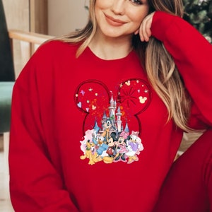 May include: Red sweatshirt with a graphic of Mickey Mouse, Minnie Mouse, Goofy, Pluto, and Donald Duck in front of Cinderella's Castle. The graphic is surrounded by a Mickey Mouse ear shape with confetti and hearts.