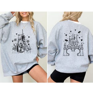 Puede incluir: Sudadera gris claro con un gr&aacute;fico en blanco y negro de un castillo y Pluto. El dise&ntilde;o frontal muestra a Pluto frente al castillo, mientras que la parte trasera presenta el contorno del castillo. Cuello redondo y mangas largas.