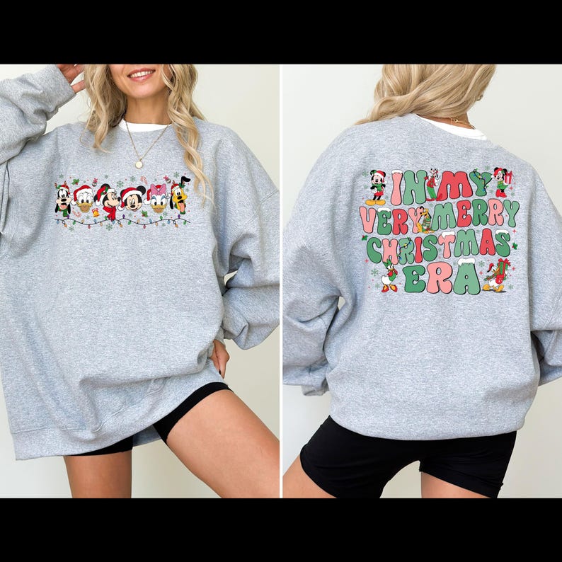 May include: A gray sweatshirt with a Christmas-themed design featuring Mickey Mouse and other Disney characters. The back of the sweatshirt says "In My Very Merry Christmas Era" with the characters surrounding the text.