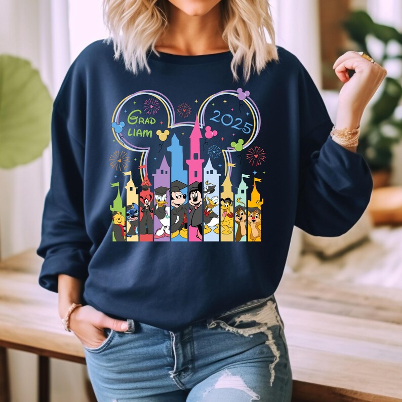 Puede incluir: Una sudadera azul marino con un gr&aacute;fico de Mickey Mouse y otros personajes de Disney frente al Castillo de Cenicienta. El gr&aacute;fico tambi&eacute;n incluye el texto "Grad Liam 2025" y fuegos artificiales.