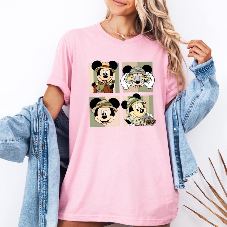 K&ouml;nnte beinhalten: Hellrosa T-Shirt mit vier Feldern, die Micky Maus in Safari-Kleidung zeigen. Jedes Feld zeigt Micky in einer anderen Pose, mit Safarihut und Fernglas oder Kamera. Die Felder haben gr&uuml;ne und beige Hintergr&uuml;nde.