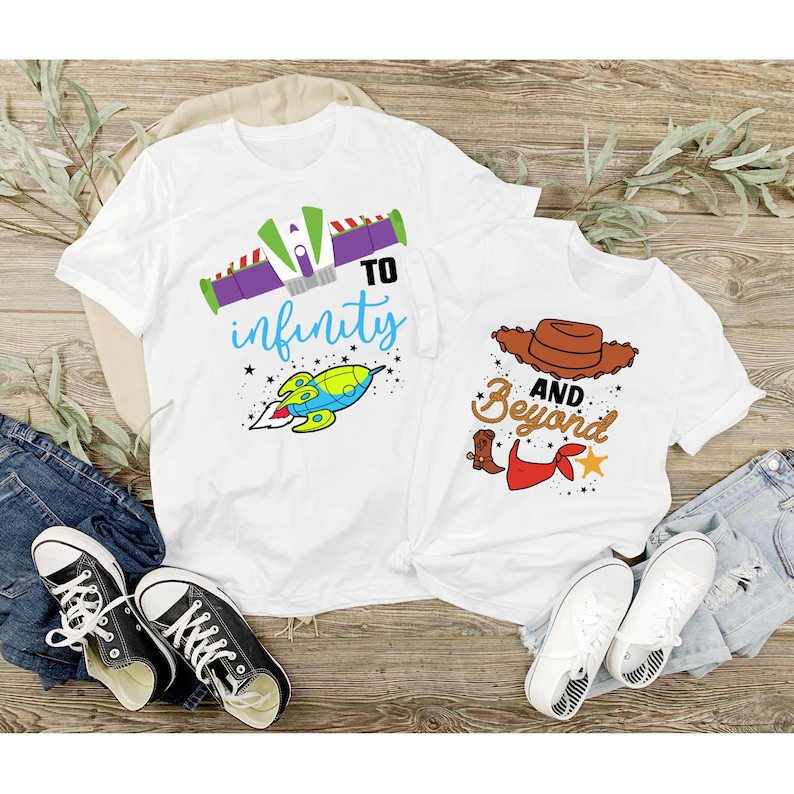 Peut inclure: Deux t-shirts blancs sur le th&egrave;me de Toy Story. Le plus grand t-shirt a une fus&eacute;e et le texte "To infinity". Le plus petit t-shirt a un chapeau de cowboy et le texte "And beyond".