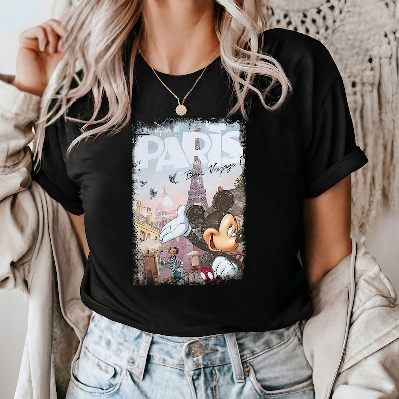 May include: Black t-shirt with a graphic print of Mickey Mouse in front of the Eiffel Tower in Paris. The graphic also includes the text "Paris Bon Voyage".