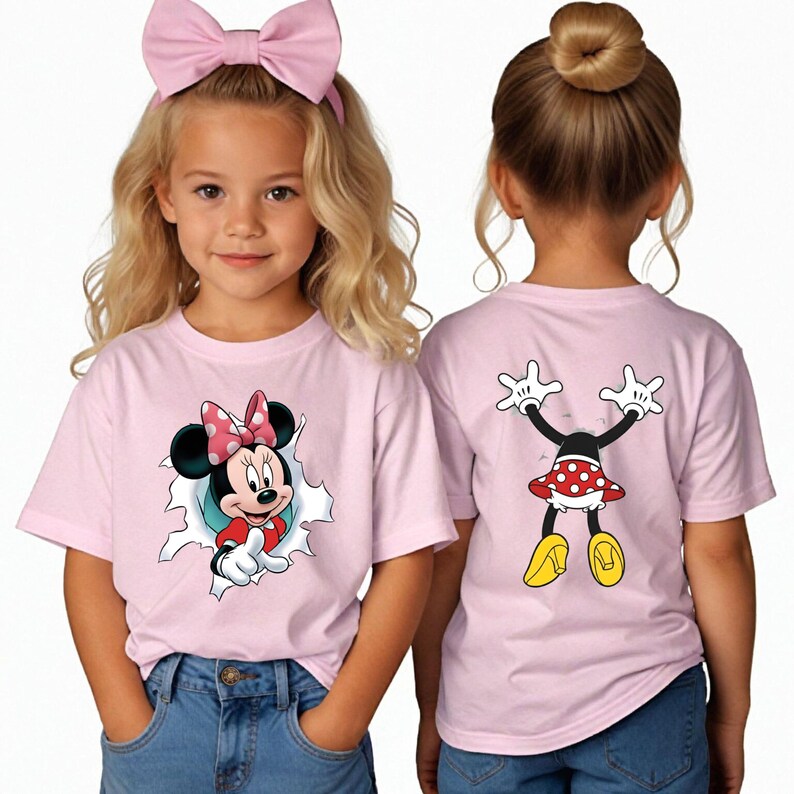 K&ouml;nnte beinhalten: Zwei junge M&auml;dchen tragen passende rosa T-Shirts mit Minnie Mouse. Auf der Vorderseite des Shirts ist Minnie Mouse zu sehen, die aus einem zerrissenen Loch herauskommt. Auf der R&uuml;ckseite des Shirts sind Minnie Mouse's Arme, Rock und gelbe Schuhe zu sehen. Ein M&auml;dchen tr&auml;gt eine rosa Schleife.