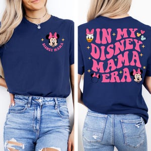 May include: A navy blue t-shirt with a pink Minnie Mouse graphic on the front and the text "In My Disney Mama Era" in pink on the back.