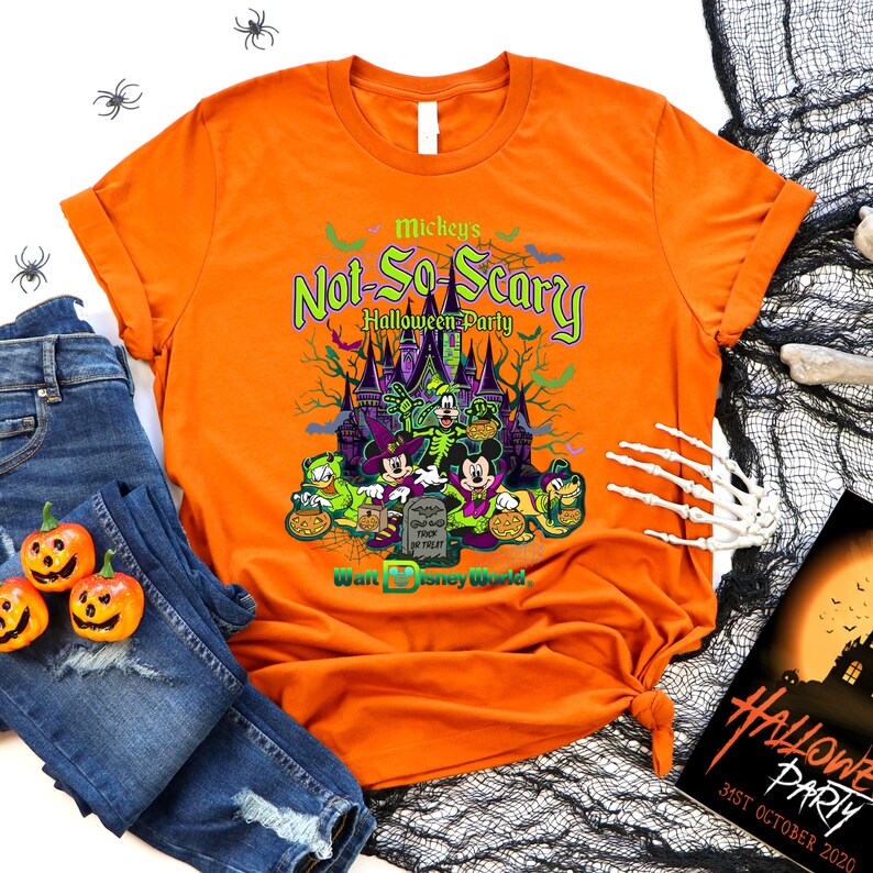 May include: Orange t-shirt with a graphic of Mickey Mouse and friends in front of a castle. The text "Mickey's Not-So-Scary Halloween Party" is printed on the shirt. The text "Walt Disney World" is also printed on the shirt.