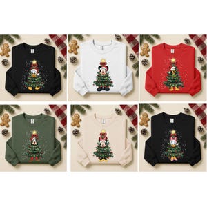 May include: A collection of Christmas-themed sweatshirts in various colors, including black, white, red, green, and beige. Each sweatshirt features a cartoon character decorated as a Christmas tree. The sweatshirts are decorated with Christmas lights and a star.