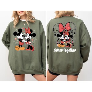 May include: Green sweatshirt with a graphic of Mickey Mouse and Minnie Mouse holding hands. The back of the sweatshirt has a graphic of Mickey and Minnie Mouse hugging with the text "Better Together".