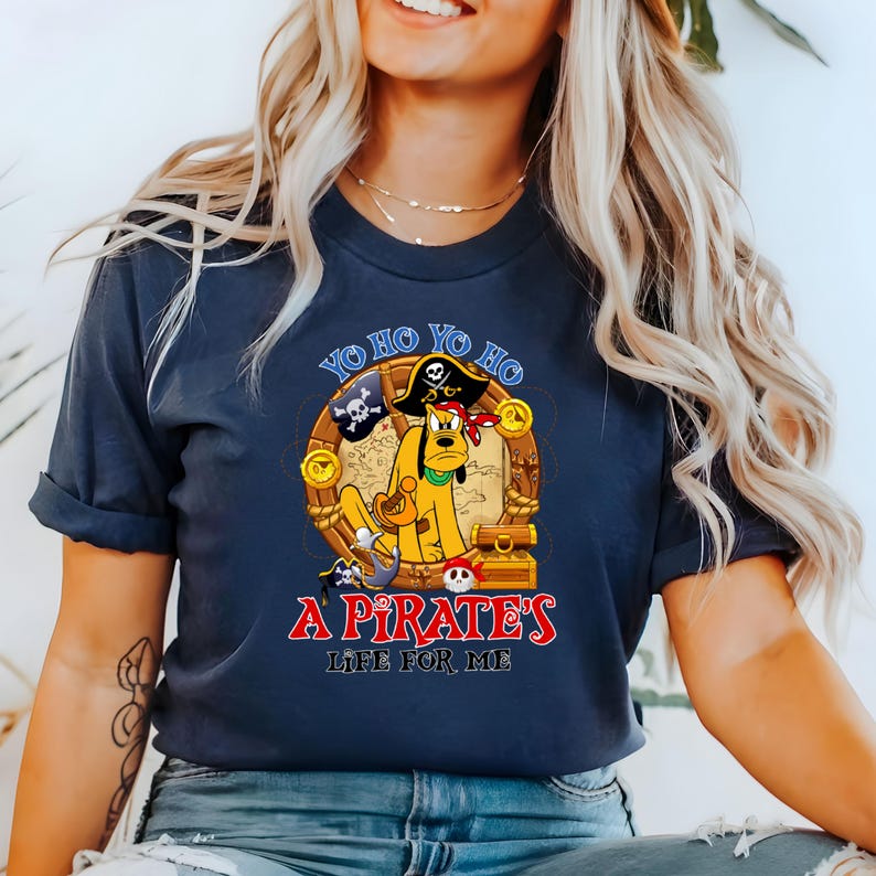 K&ouml;nnte beinhalten: Ein marineblaues T-Shirt mit einem Cartoon-Hund, der einen Piratenhut tr&auml;gt und eine Schatztruhe h&auml;lt. Der Text auf dem Shirt lautet "Yo ho yo ho a pirate's life for me."