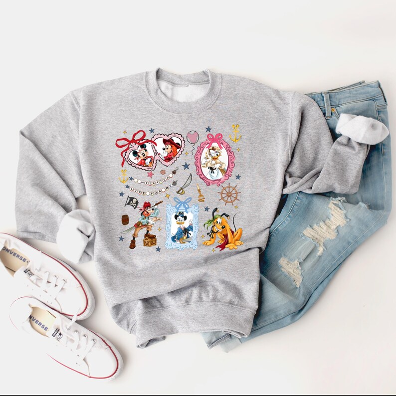 May include: A gray sweatshirt with a colorful print of Disney characters in frames. The characters include Mickey Mouse, Minnie Mouse, Donald Duck, Goofy, and Pluto. The print also includes hearts, stars, and anchors.