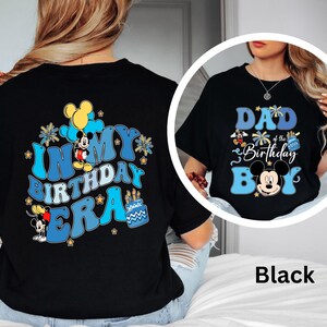 Op de afbeelding: Zwarte T-shirts met Mickey Mouse-ontwerpen. E&eacute;n shirt zegt "IN MY BIRTHDAY ERA" met Mickey Mouse en verjaardagstaartafbeeldingen. De andere zegt "DAD of the Birthday BOY" met Mickey Mouse-afbeeldingen.