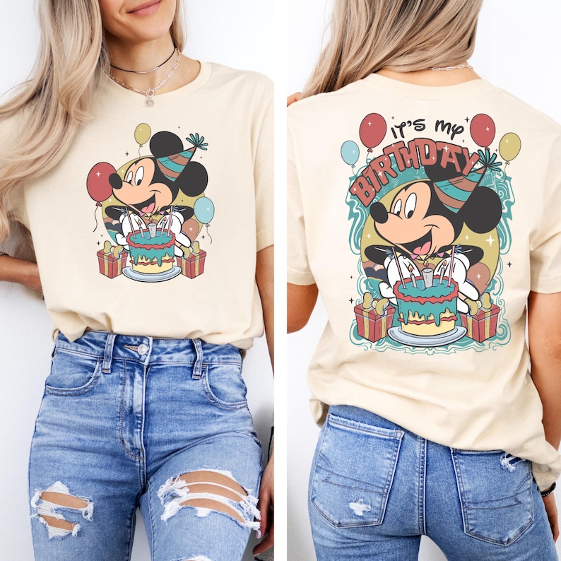 以下が含まれることがあります： ベージュのTシャツに、ミッキーマウスが誕生日ケーキとろうそくを持っているヴィンテージスタイルのグラフィックがプリントされています。Tシャツの後ろには「It's my Birthday」という文字がプリントされています。