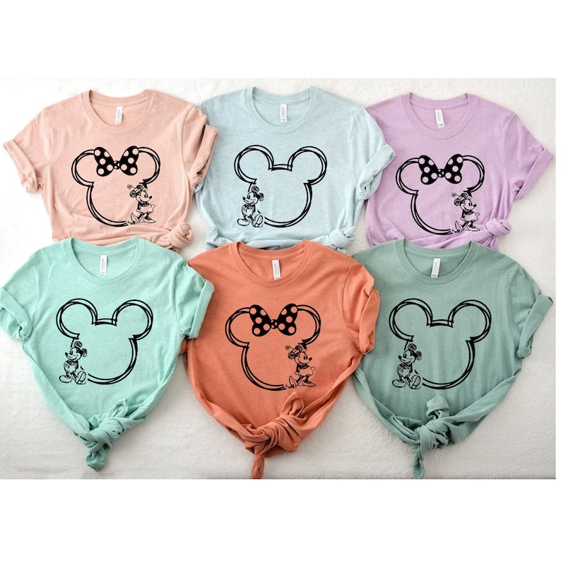 May include: Six t-shirts with a black and white outline of Mickey Mouse's head with Minnie Mouse standing inside. The shirts are in various colors: light pink, light blue, lavender, light green, peach, and dark green.