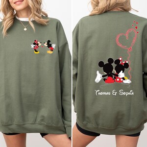 May include: A green sweatshirt with a Mickey Mouse and Minnie Mouse graphic on the front and a Mickey Mouse and Minnie Mouse graphic with a heart and the text "Thomas & Sophia" on the back.