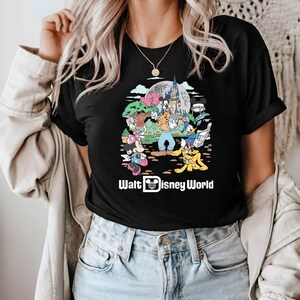 May include: Black t-shirt with a colorful graphic of Mickey Mouse, Minnie Mouse, Donald Duck, Goofy, and Pluto in front of Cinderella's Castle. The text "Walt Disney World" is printed below the graphic.