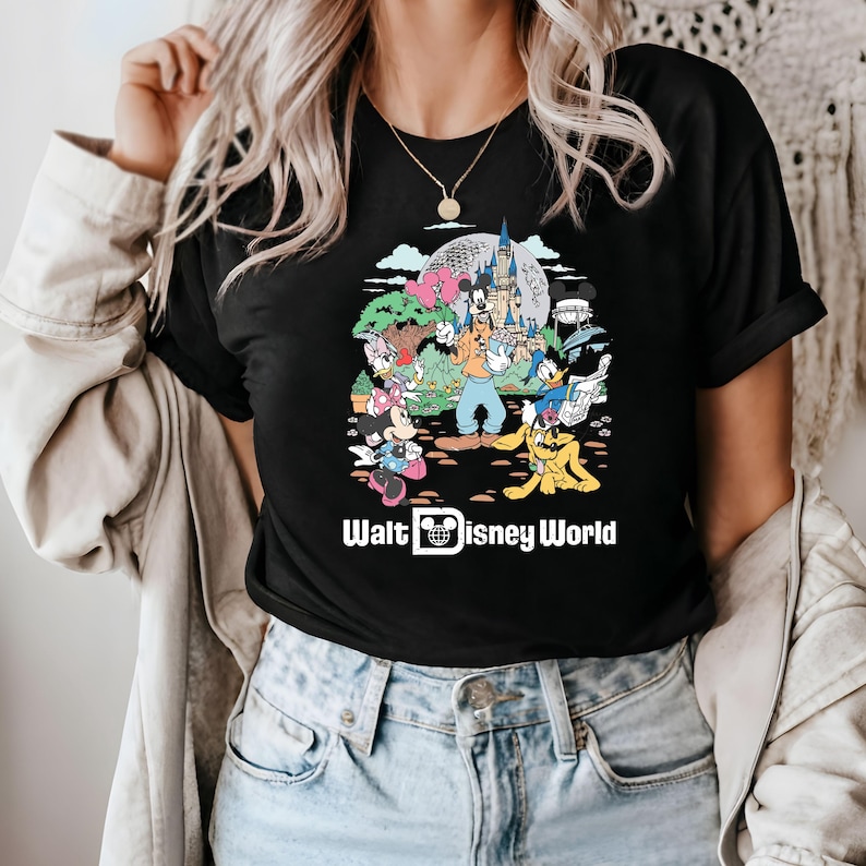 May include: Black t-shirt with a colorful graphic of Mickey Mouse, Minnie Mouse, Donald Duck, Goofy, and Pluto in front of Cinderella's Castle. The text "Walt Disney World" is printed below the graphic.