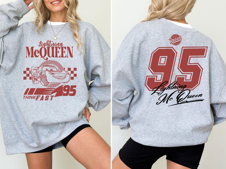 May include: Gray sweatshirt with a red and black graphic of Lightning McQueen from the Cars movie. The graphic includes the text "Lightning McQueen", "Think Fast", and "95". The back of the sweatshirt has a large red number "95" with the text "Lightning McQueen" underneath.