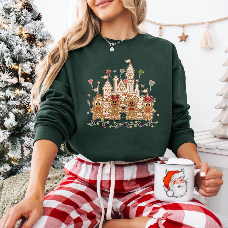 Może przedstawiać: Zielony świąteczny sweter z zamkiem z piernika i postaciami z piernika. Postacie to Myszka Miki, Minnie Mouse, Donald Duck i Goofy. Sweter ma świąteczny wz&oacute;r i idealnie nadaje się na okres świąteczny.