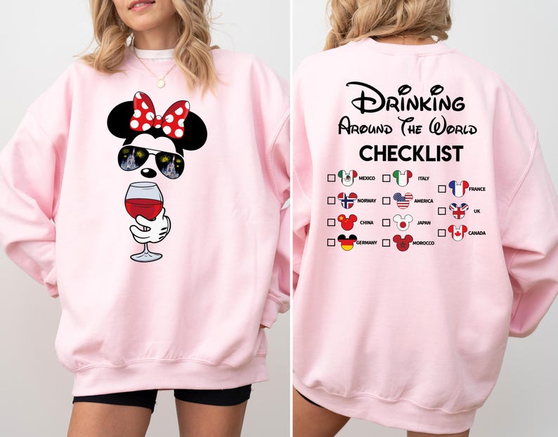 Puede incluir: Sudadera rosa con un dise&ntilde;o de Mickey Mouse bebiendo vino. La parte posterior de la sudadera tiene una lista de verificaci&oacute;n de pa&iacute;ses con banderas y el texto "Drinking Around the World Checklist".
