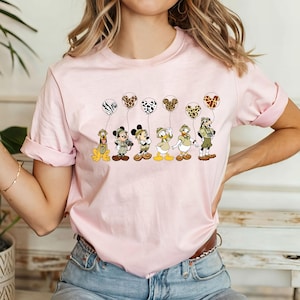 Pode incluir: Camiseta rosa com um gr&aacute;fico de Mickey Mouse, Donald Duck, Pateta e Pluto vestidos com roupas de saf&aacute;ri segurando bal&otilde;es com estampa de animais.