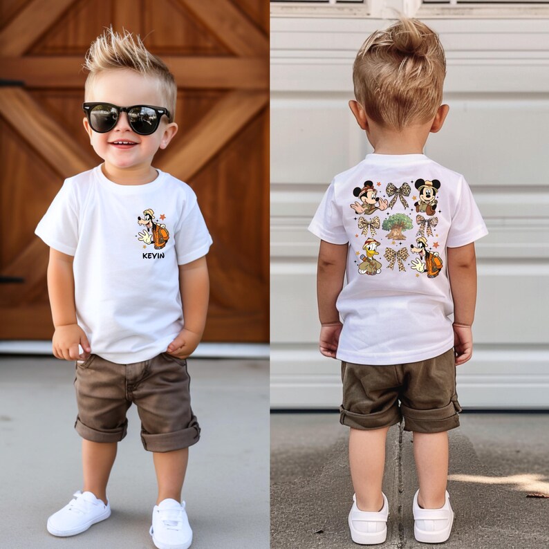 May include: A white t-shirt with a cartoon image of Goofy and the text "Kevin" on the front. The back of the shirt features a design with Mickey Mouse, Minnie Mouse, Donald Duck, and other Disney characters. The shirt is being worn by a young boy wearing brown shorts.