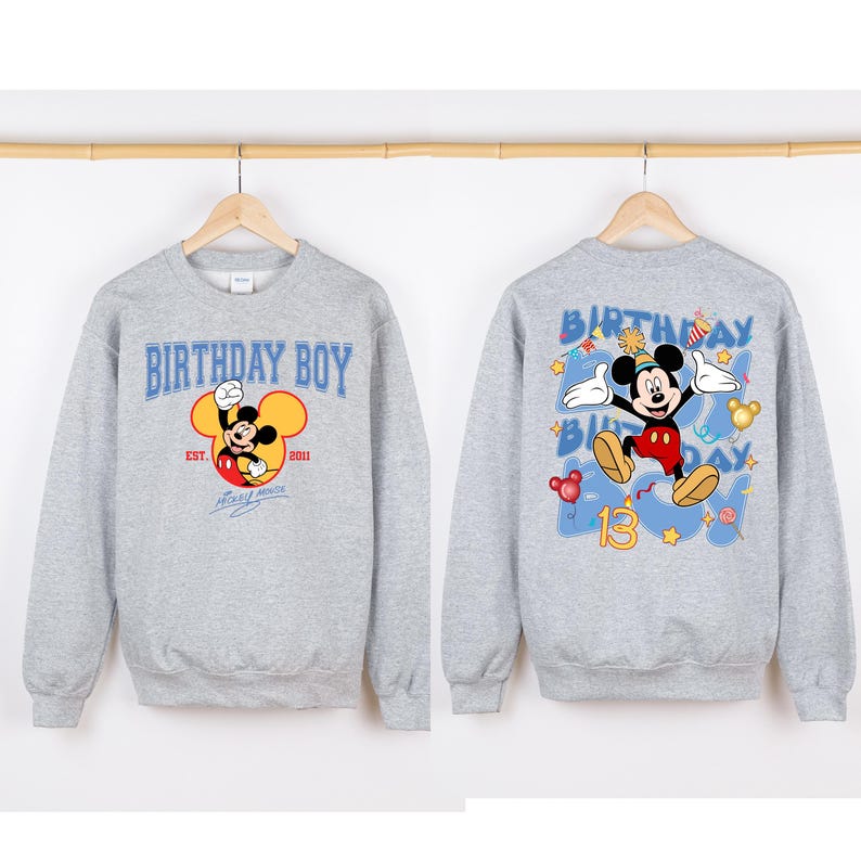 May include: Grey sweatshirt with a Mickey Mouse graphic on the front. The front graphic says "Birthday Boy" with "Est. 2011" and "Mickey Mouse" underneath. The back of the sweatshirt has a larger Mickey Mouse graphic with the words "Birthday Boy" and the number "13" in blue.