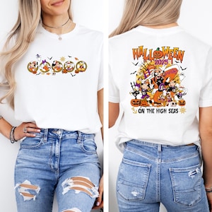 May include: White t-shirt featuring a Halloween-themed graphic. The front of the shirt displays cartoon characters in Halloween costumes. The back of the shirt has a larger design with the text "Halloween 2025" and "On the High Seas."