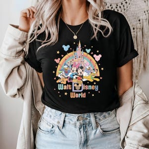 Puede incluir: Camiseta negra con un gr&aacute;fico colorido de Mickey Mouse y sus amigos frente al castillo de Disney. El texto "Walt Disney World" est&aacute; impreso debajo del gr&aacute;fico.