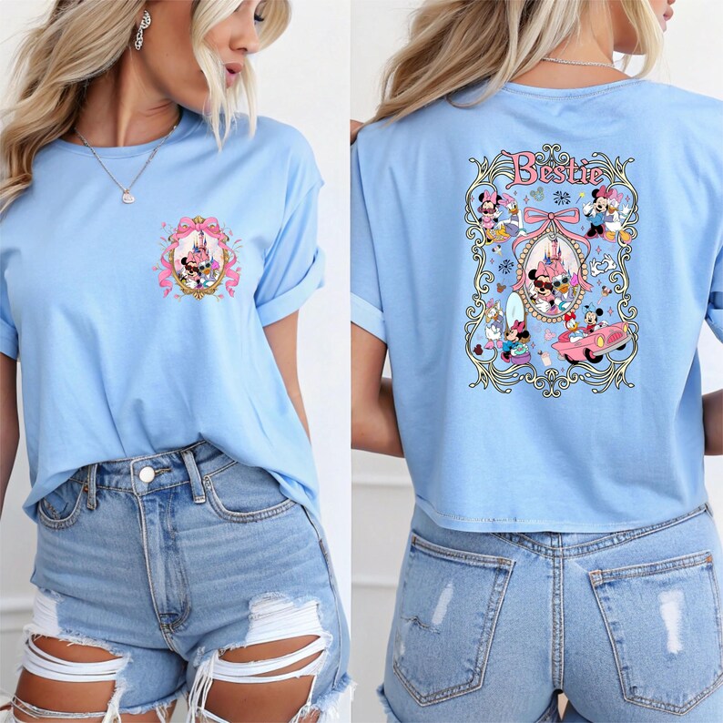 May include: A light blue t-shirt with a graphic of Mickey Mouse and friends in front of a pink castle on the front and the word "Bestie" with a graphic of Mickey Mouse and friends on the back.