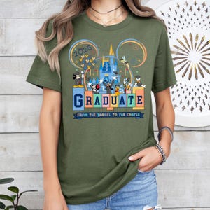 May include: Green t-shirt with a graphic of Mickey Mouse and friends celebrating graduation at Disney World. The text on the shirt reads "2025 Graduate From the Tassel to the Castle".