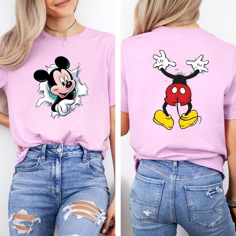 Puede incluir: Camiseta rosa claro con un gr&aacute;fico de Mickey Mouse. La parte delantera de la camiseta muestra a Mickey Mouse saliendo de un agujero rasgado. La parte trasera de la camiseta muestra la parte trasera de Mickey Mouse. La camiseta se combina con vaqueros azules.
