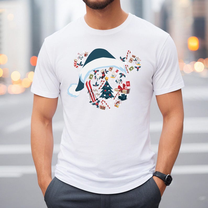May include: White t-shirt featuring a Christmas-themed design. The graphic includes a blue and white Santa hat shape filled with Christmas elements like a tree, gifts, and candy canes. The shirt has short sleeves and a crew neck.