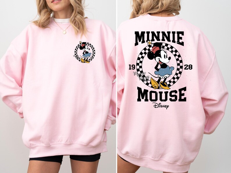 May include: Pink sweatshirt with a black and white checkered graphic featuring Minnie Mouse and the text "Minnie Mouse Disney" on the back. The front of the sweatshirt has a small graphic of Minnie Mouse.