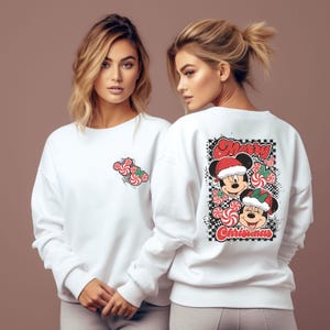 May include: White sweatshirt featuring a Mickey Mouse and Minnie Mouse Christmas design. The front has a small candy cane graphic, while the back displays a larger graphic with the words "Merry Christmas".