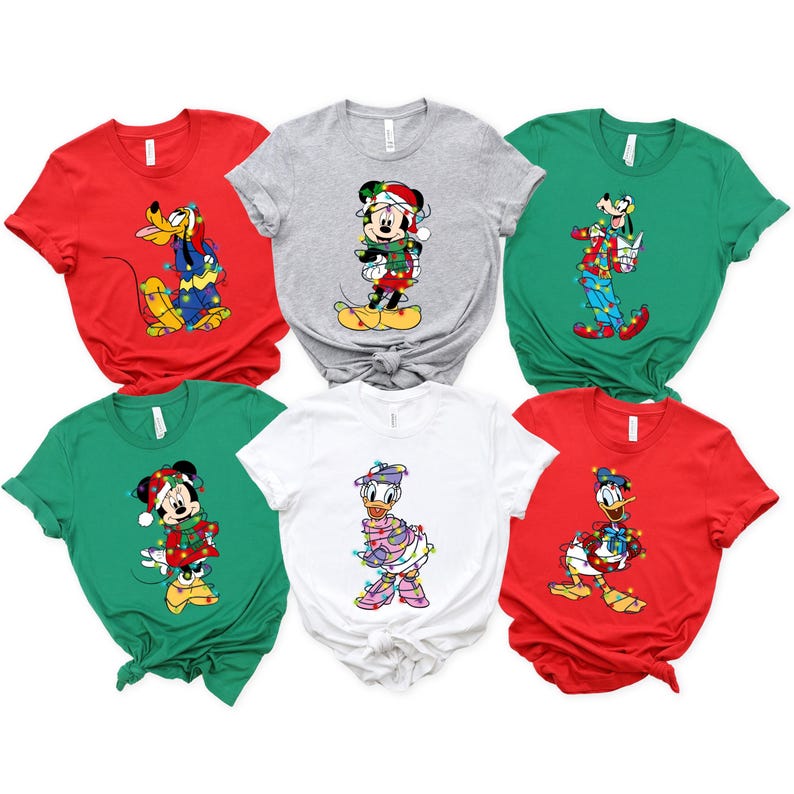K&ouml;nnte beinhalten: Sechs kurz&auml;rmelige T-Shirts in Rot, Gr&uuml;n, Grau und Wei&szlig;. Jedes Shirt zeigt einen anderen Disney-Charakter, darunter Micky und Minnie Maus, Donald und Daisy Duck sowie Goofy, alle mit Weihnachtsbeleuchtung geschm&uuml;ckt.