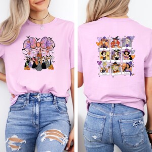 May include: A light pink t-shirt featuring a Halloween-themed graphic on the front and back. The front design includes a bow, castle, and characters. The back displays nine character portraits. The shirt is made of a soft material.