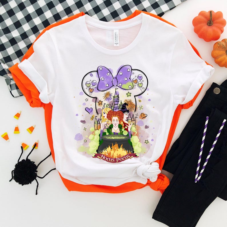 May include: White t-shirt with a purple and white bow, a cartoon image of the Sanderson sisters from Hocus Pocus, and the text "Hocus Pocus".