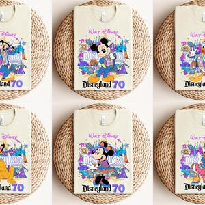 May include: Six beige t-shirts with different Disney characters on them. Each shirt has the text "Walt Disney" and "Disneyland 70" on it. The characters are Mickey Mouse, Donald Duck, Goofy, and Minnie Mouse.