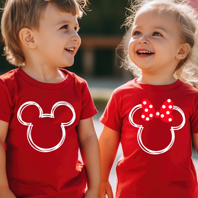 May include: Two children wearing red t-shirts with white Mickey Mouse and Minnie Mouse silhouettes. The girl's shirt has a red polka dot bow on Minnie Mouse's head.