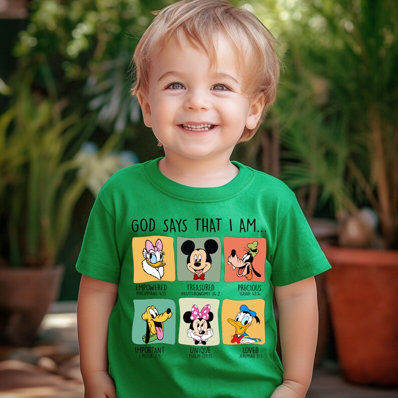 Puede incluir: Una camiseta verde con personajes de Disney y el texto "GOD SAYS THAT I AM...". La camiseta incluye im&aacute;genes de Daisy, Mickey Mouse, Goofy, Pluto, Minnie Mouse y Donald, con palabras como "Empowered" y "Loved".