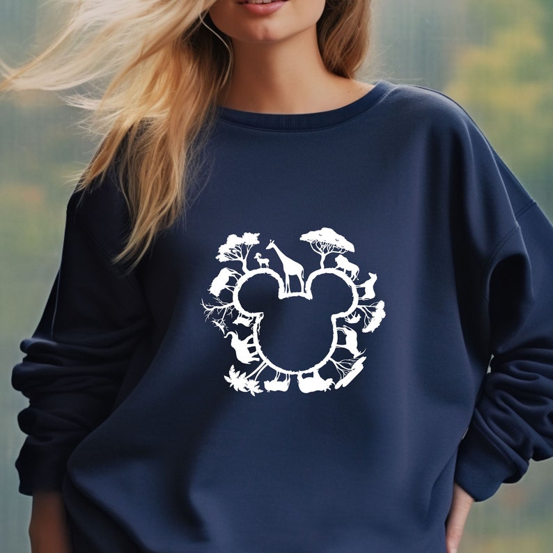 May include: A navy blue sweatshirt featuring a white silhouette of Mickey Mouse's head. Inside the silhouette are various animals, including a giraffe, elephant, and zebra, surrounded by trees.