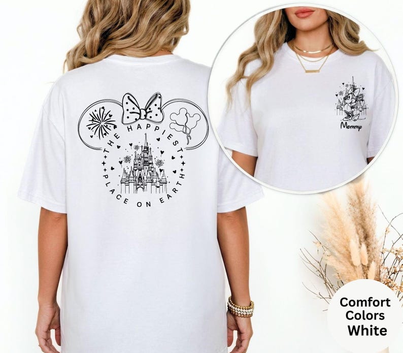 May include: White t-shirt with a black graphic on the back featuring a castle, fireworks, and the text "THE HAPPIEST PLACE ON EARTH." The front of the shirt has a smaller graphic with the word "Mommy."