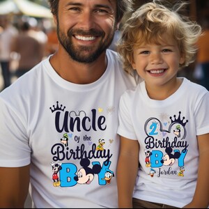 May include: Two white t-shirts with a Mickey Mouse theme. The larger shirt says "Uncle of the Birthday Boy" with Mickey Mouse and friends. The smaller shirt says "2 Birthday Boy Jordan" with Mickey Mouse and friends.