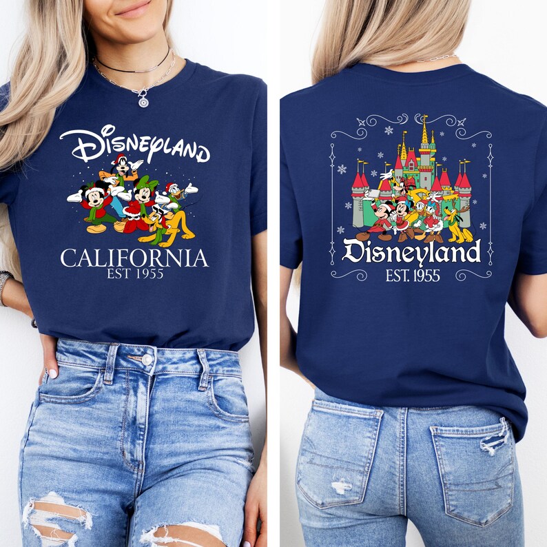May include: Navy blue t-shirt featuring Disneyland graphics. The front displays the Disneyland logo with cartoon characters and the text "CALIFORNIA EST 1955." The back shows a castle graphic with characters and the Disneyland logo.