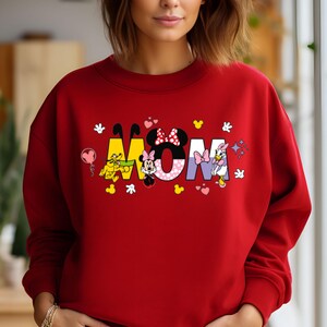 May include: Red sweatshirt with a graphic of Mickey Mouse characters spelling out the word "MOM".