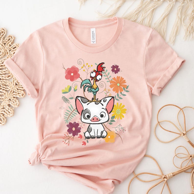 Puede incluir: Una camiseta rosa con una imagen de dibujos animados de un cerdo y un gallo en un dise&ntilde;o floral.