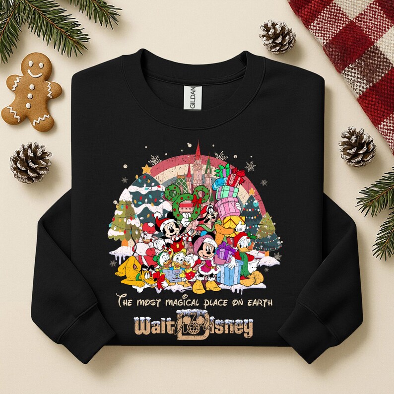 Op de afbeelding: Zwarte crewneck sweatshirt met een kleurrijke afbeelding van Disney-personages, kerstbomen en een regenboog. De tekst "The most magical place on earth" en "Walt Disney" staan eronder gedrukt.