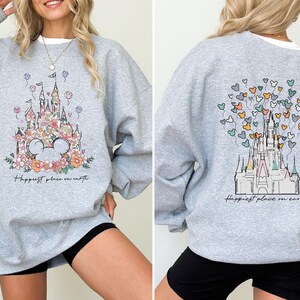 May include: A gray sweatshirt with a floral print of Cinderella's castle and the text "Happiest place on earth".