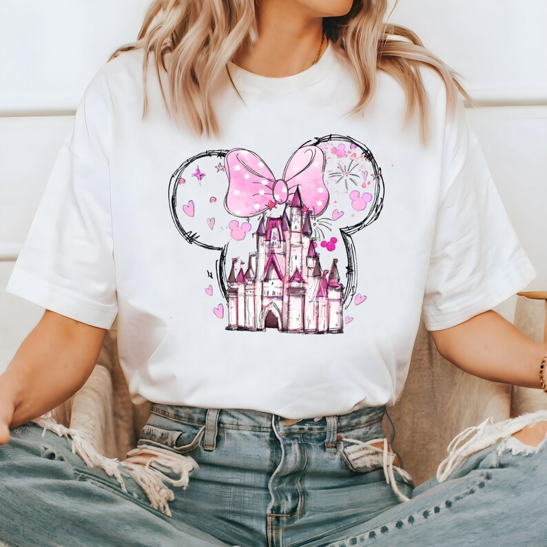 May include: White t-shirt with a pink bow and a pink castle graphic. The castle is surrounded by hearts and stars.